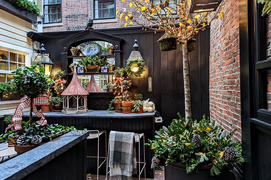 A small open-air courtyard is surrounded by brick walls and decorated like a cozy cafe.