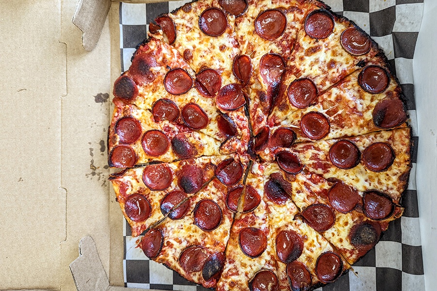 Overhead view of a pepperoni pizza with a barely-there, charred crust.