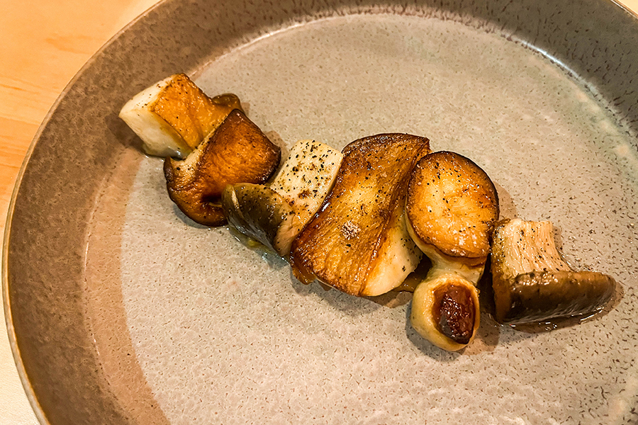 Plump mushrooms with charred edges are lined up across a plate.