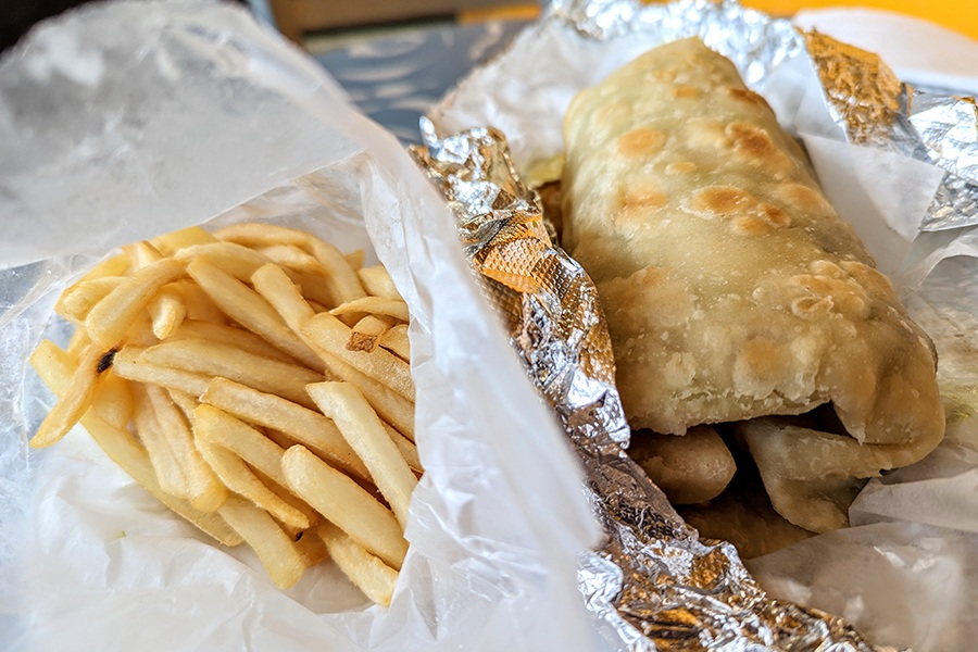 Roti is tightly wrapped around unseen fillings, like a burrito. There's a side of fries.