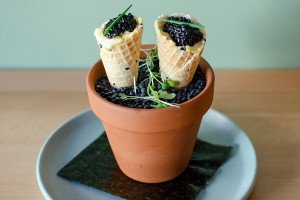 Two small ice cream cones full of caviar are presented in a little terracotta flower pot.