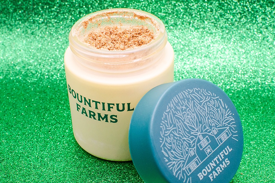 A small, round container with Bountiful Farms branding is open to reveal a light brown powder.