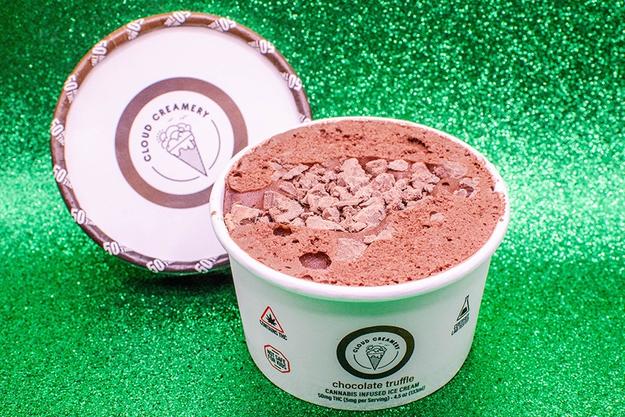 A small white cup with Cloud Creamery branding is full of chocolate ice cream with crunchy bits on top.