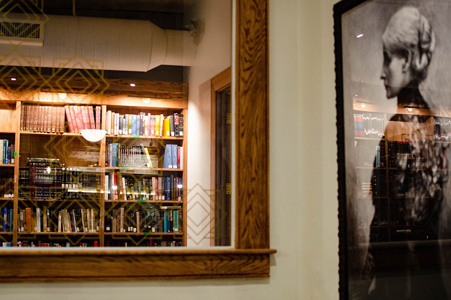 An interior window of a restaurant peeks into a private room full of bookshelves.