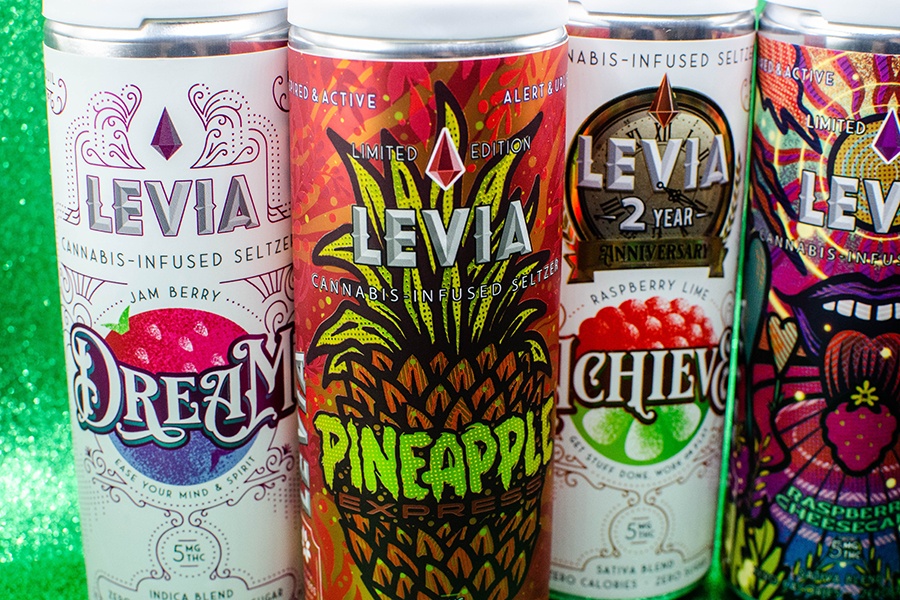 Four cannabis-infused seltzer cans with bold artwork are lined up.