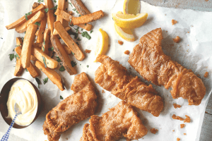 Overhead view of crispy pieces of fried fish accompanied by fries and lemon slices.