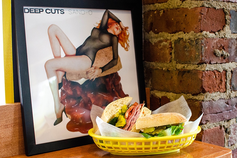 An Italian sandwich in a yellow basket is displayed in front of a parody of the Cars' Candy-O album cover.