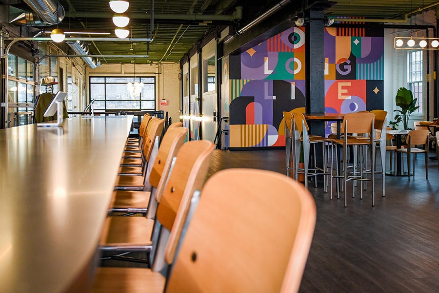 A multi-level taproom includes high- and low-top seating, bar space, and a colorful mural with the words Long Live.