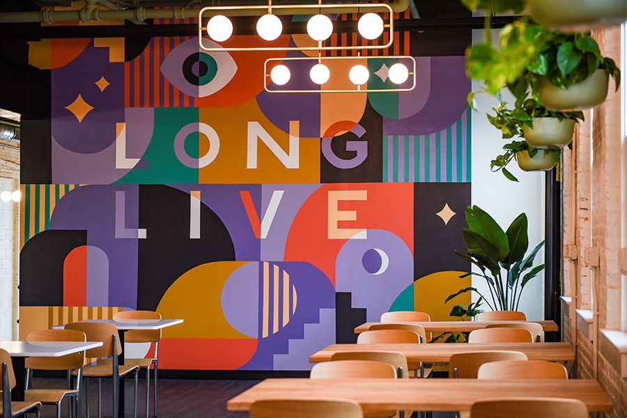 A brewery features plants, light wooden accents, and a colorful mural that says Long Live.