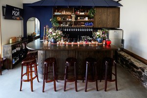 A small bar features 8 translucent amber stools, ash wood, and a dark blue backbar.