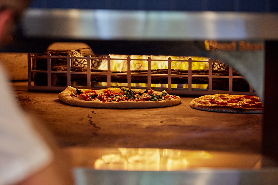 Two pizzas cook inside a large oven.