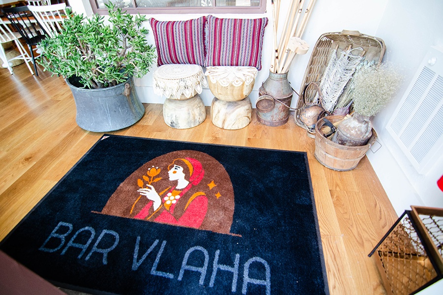 A floormat says Bar Vlaha and is surrounded by knickknacks from rural Greece.