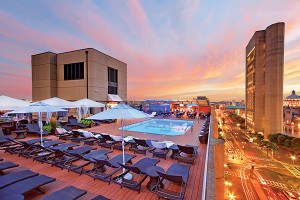 Sunset over a rooftop pool high up in a city.
