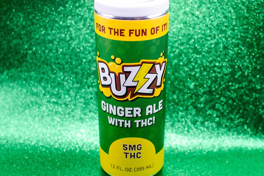A green can of THC-infused ginger ale is displayed on a sparkly green background.
