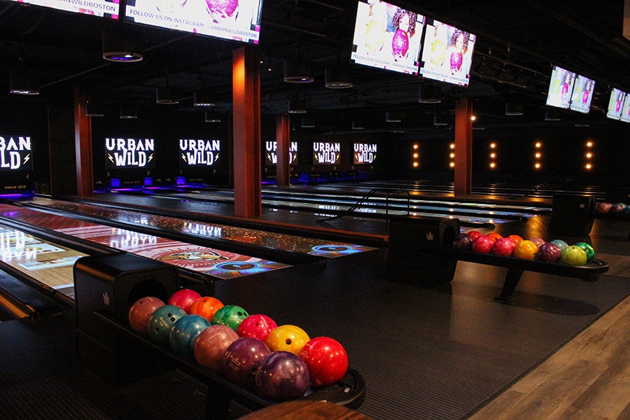 Dimly lit bowling lanes with colorful balls and signs reading Urban Wild.