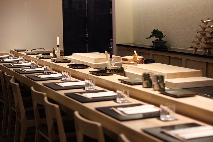 A light wooden sushi bar with seating for about eight.