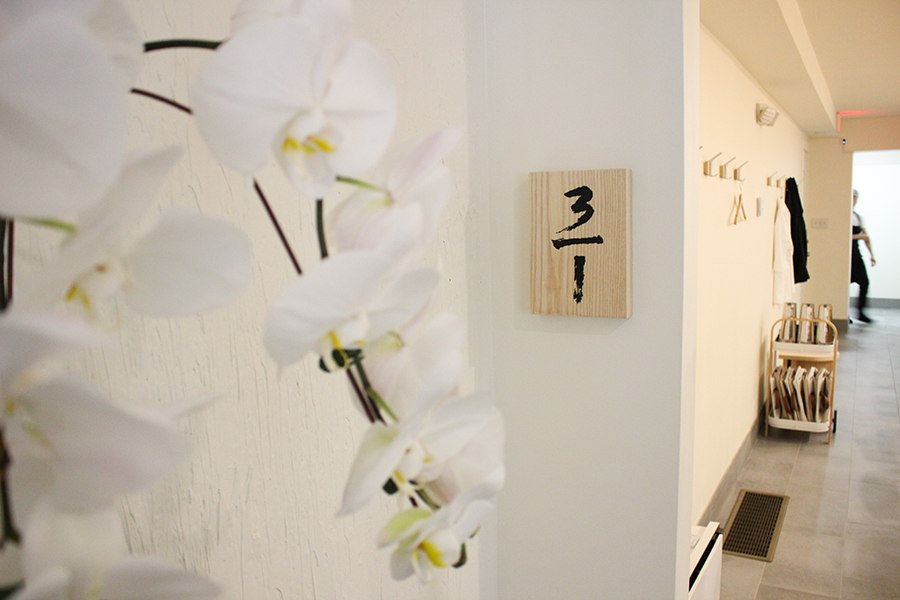 A brightly lit hallway leads into a restaurant, decorated with white orchids.