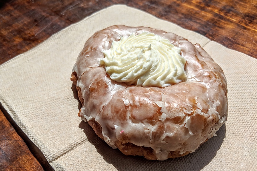 A glazed doughnut has a swirl of cream filling in the center.
