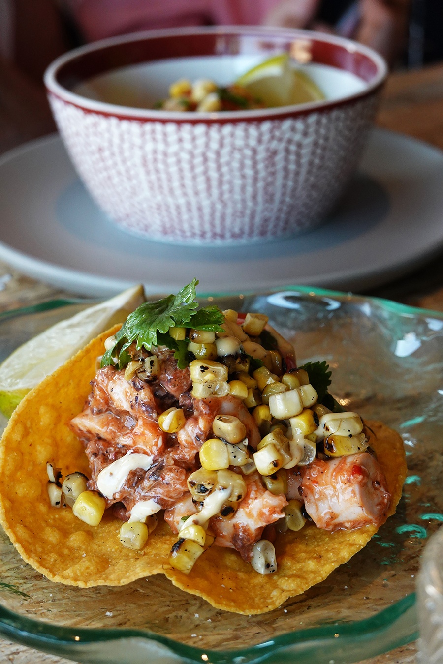 Chunks of octopus in a spicy red sauce are mixed with charred corn kernels, served on a crispy tortilla.