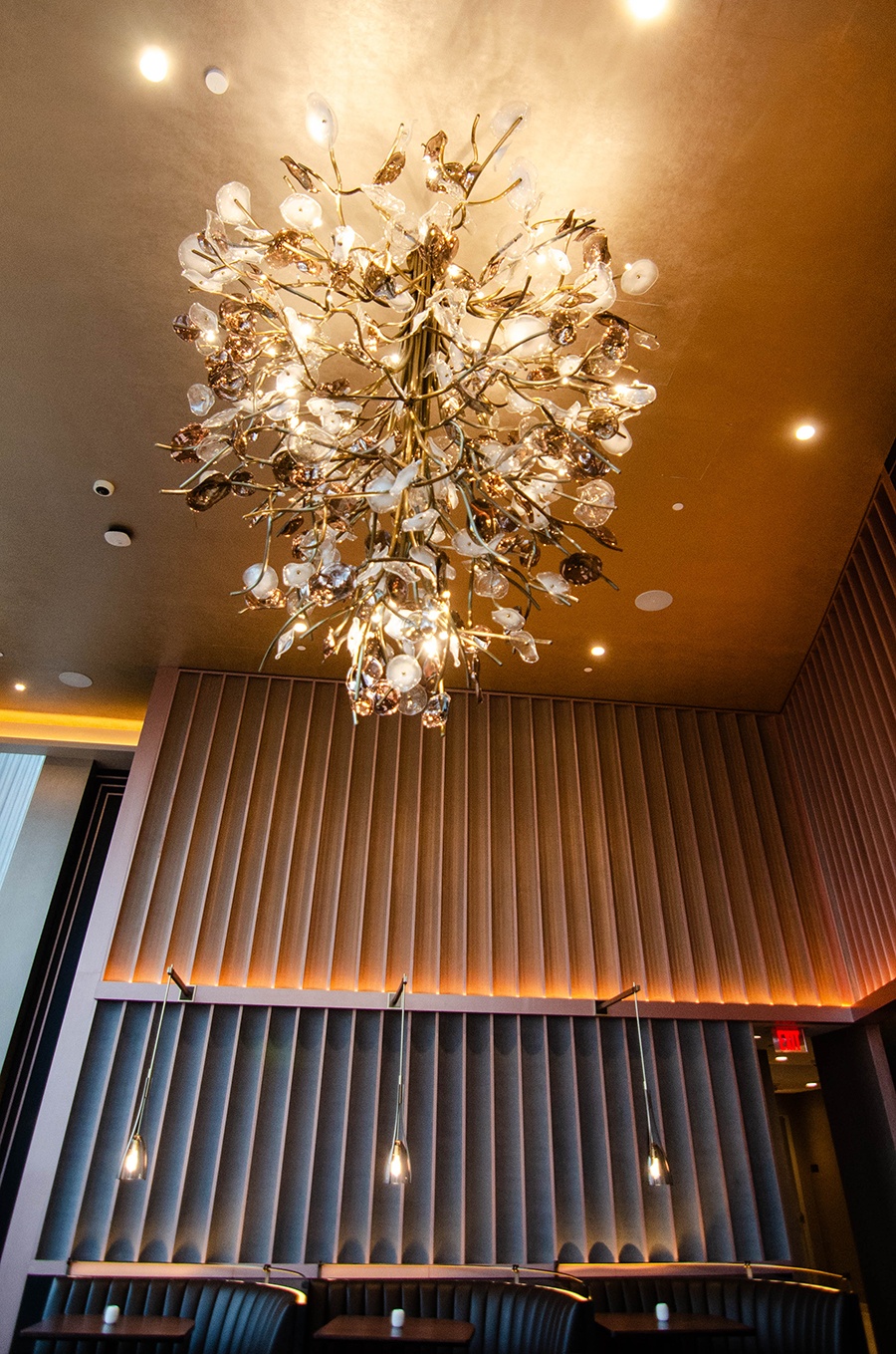 A dramatic chandelier hangs above a tall upscale restaurant.