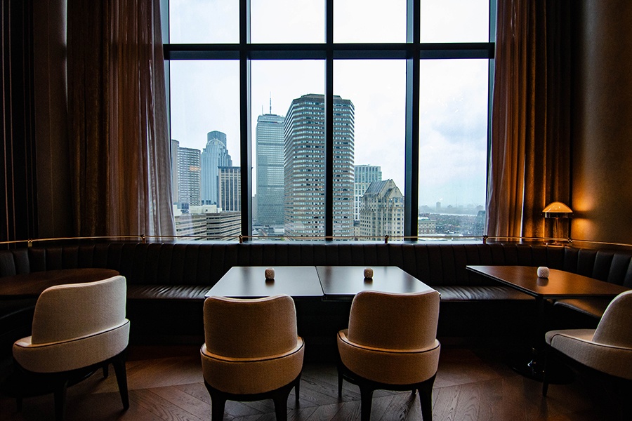 An upscale restaurant dining room's large windows look out at the Boston skyline, with the Prudential Center visible.