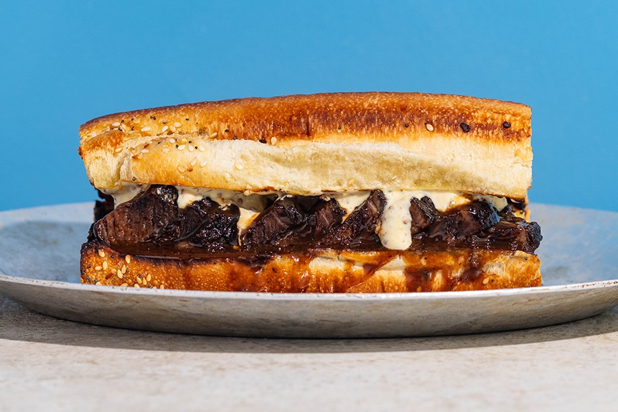 A long sandwich features saucy chunks of beef on a toasted baguette.