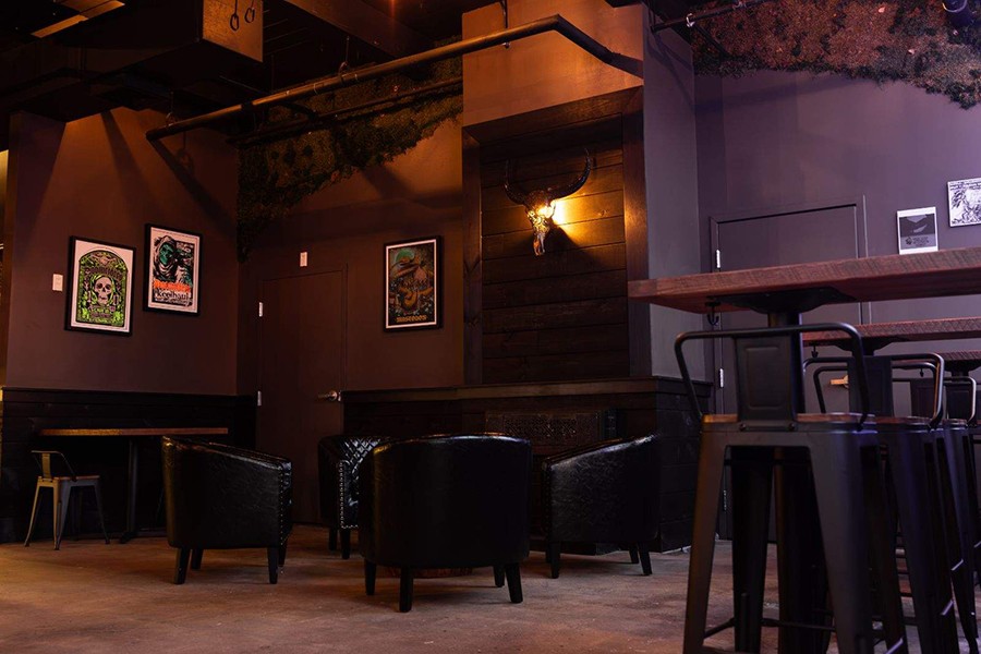 Lounge-style seating and skull-themed images decorate a taproom with black walls.