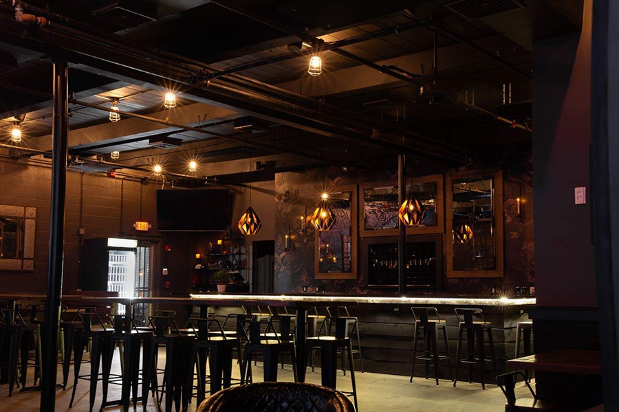 A dark taproom has black walls and goth vibes.