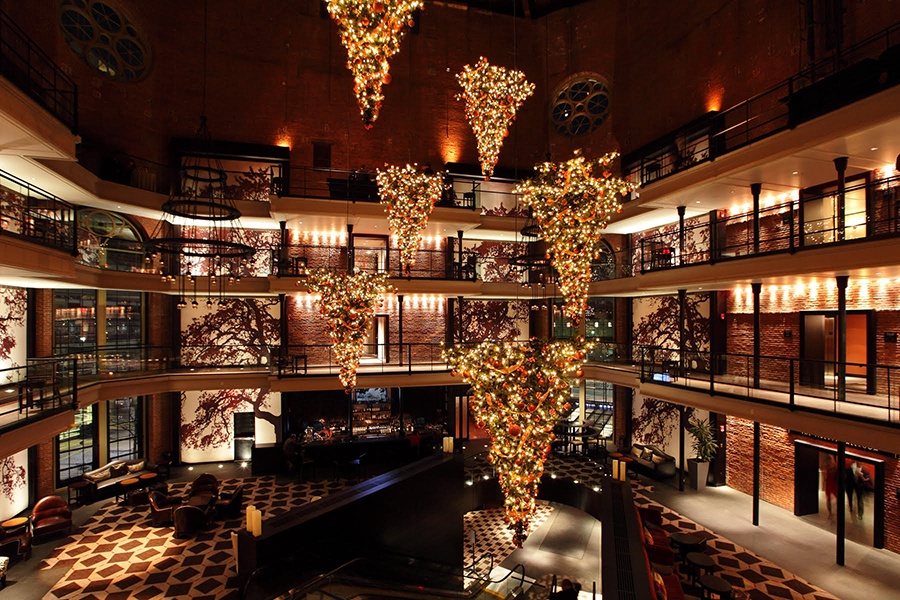 The tall atrium of a hotel lobby features full-sized Christmas trees dangling upside down.