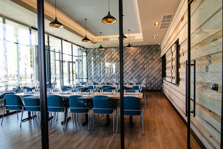 A private dining room inside a restaurant features light reclaimed wood, lots of natural light, and a wall that looks like fish scales.