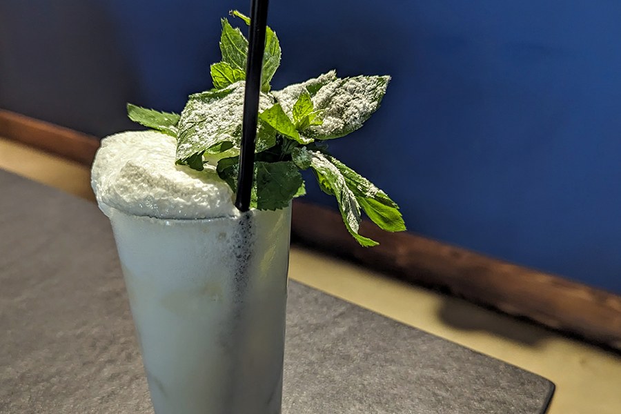 A foamy pale green cocktail is topped with lots of fresh mint.