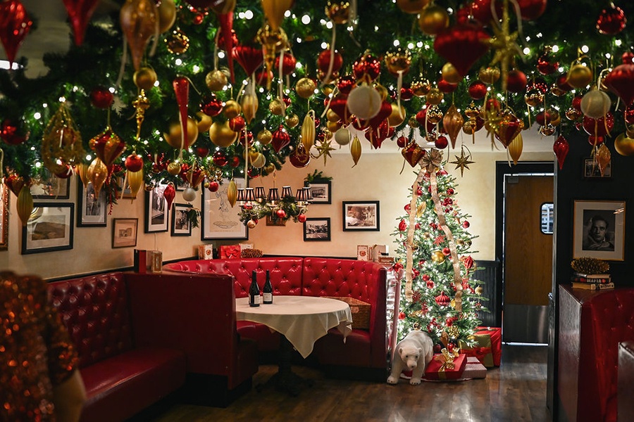 A restaurant with shiny red booths is decorated for Christmas with a tree and tons of ornament-bedecked garlands covering the ceiling.