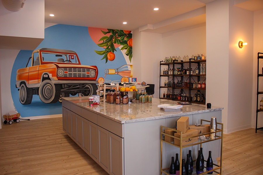 Interior of a nonalcoholic bottle shop with a large marble island and a bright mural featuring an orange Bronco.