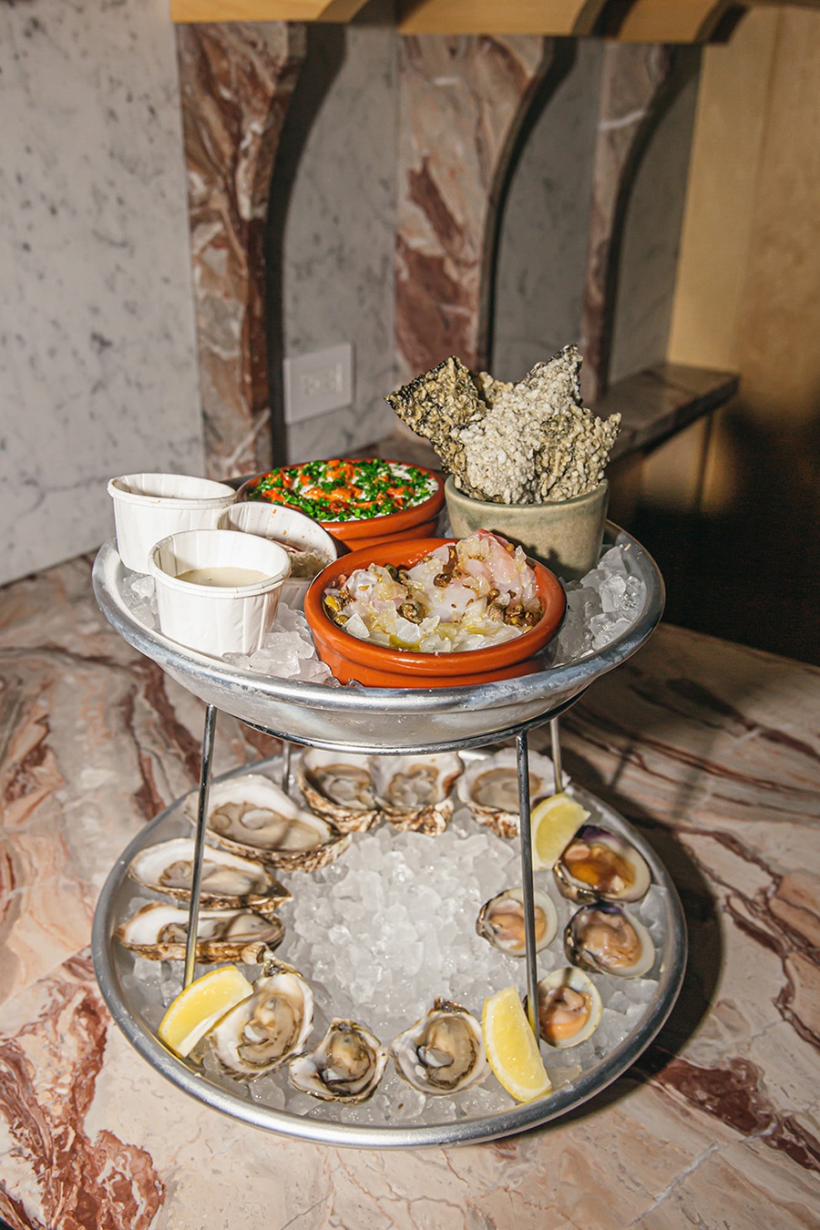 A two-tier seafood tower includes oysters, clams, crudo, and more.