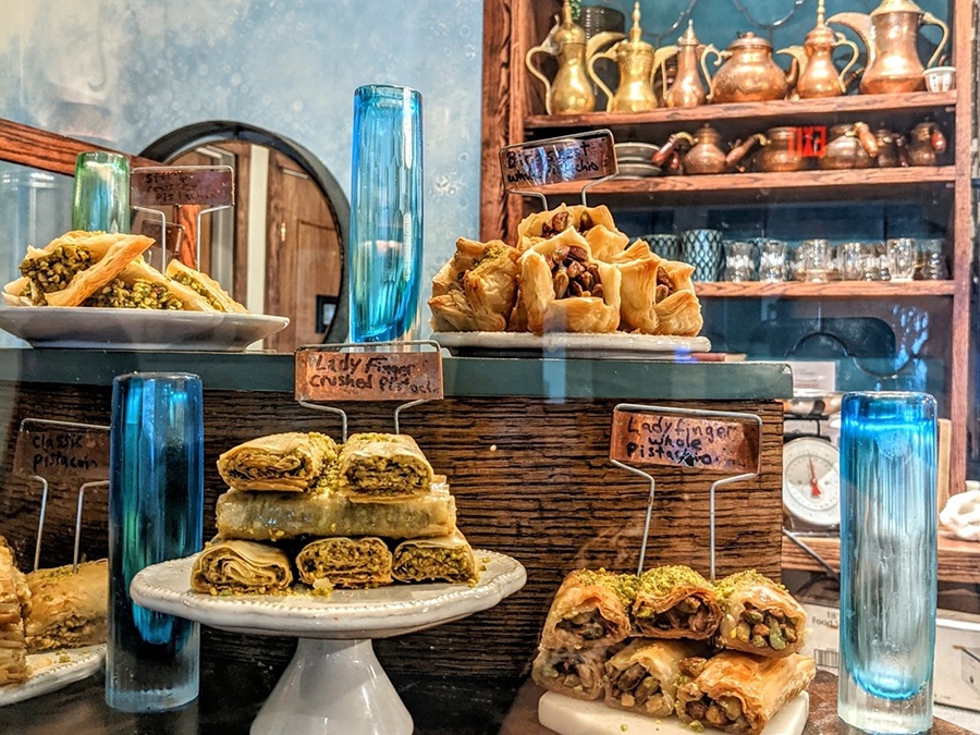 A pastry display case inside a restaurant showcases different types of baklava and other pastries.