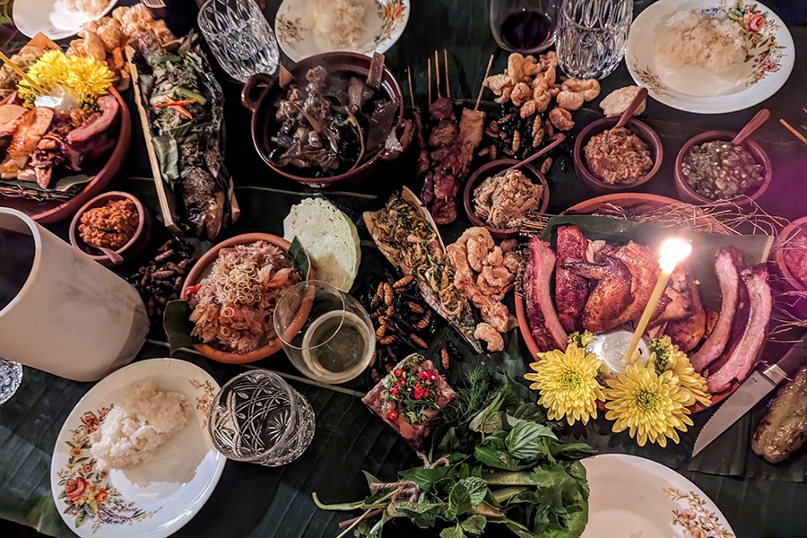 Overhead view of various Thai dishes spread over a banana leaf-covered table.