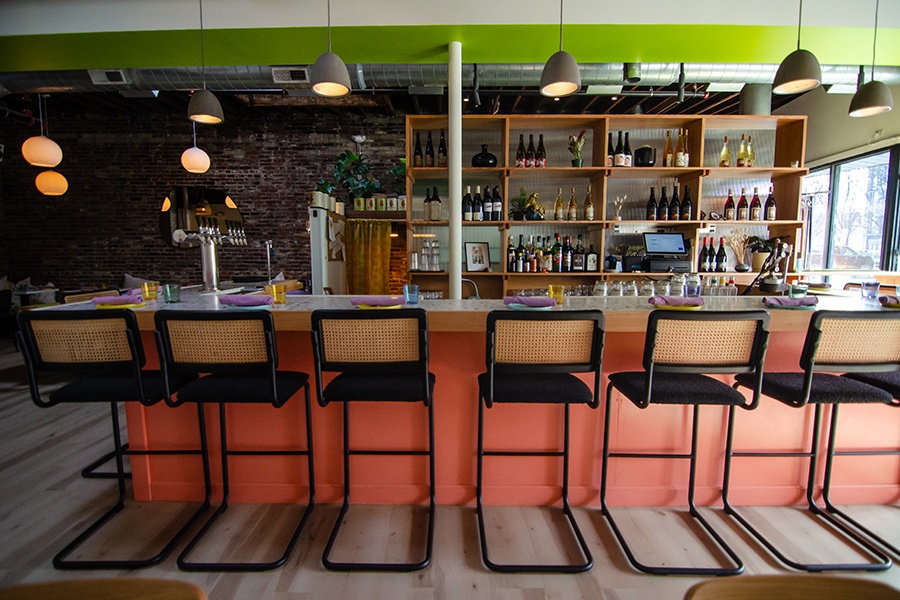 A restaurant bar with peach and bright green accents and a light wooden backbar.