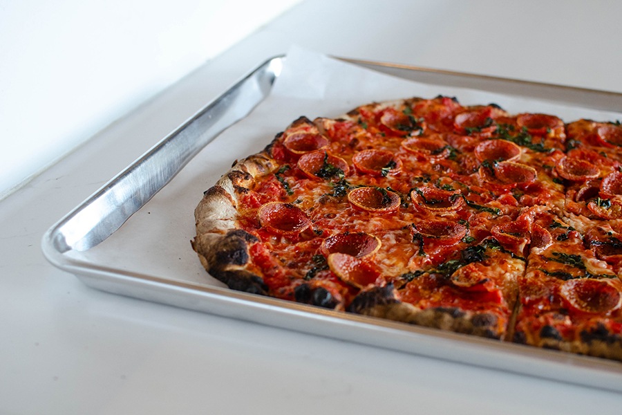 Side view of a pepperoni pizza with a thin, charred crust.