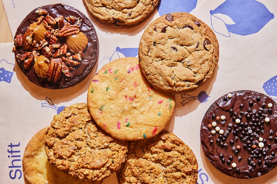 Overhead view of a variety of cookies on tissue paper.