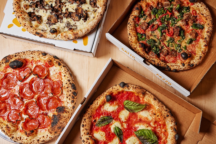 Overhead view of four different pizzas, each with a leopard-spotted, puffy crust.