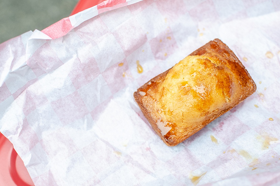 A rectangle of honey-topped cornbread sits on white-and-red-checkered paper.