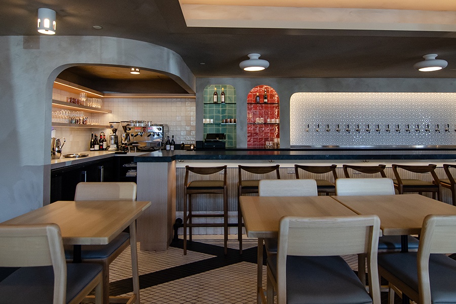 An empty restaurant space features a bar with colorful tiling behind it.