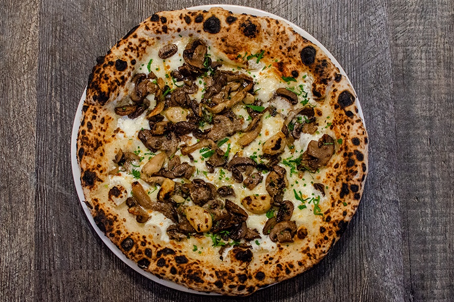 Overhead view of a mushroom pizza on a wooden surface.