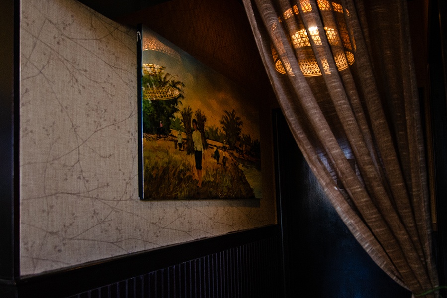 A dark corner of a restaurant features a painting of Vietnam.