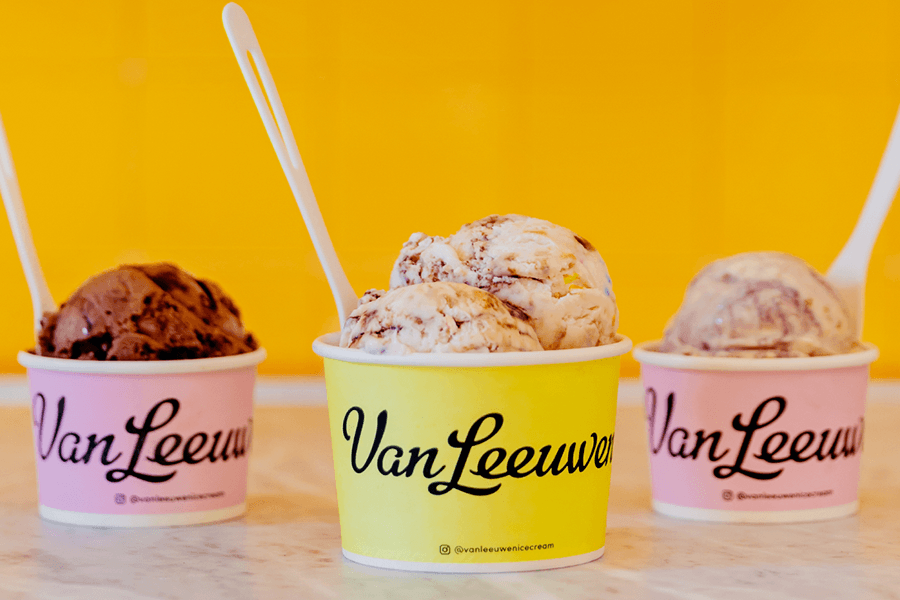 Three cups of ice cream with Van Leeuwen branding in cursive sit in front of a yellow background.