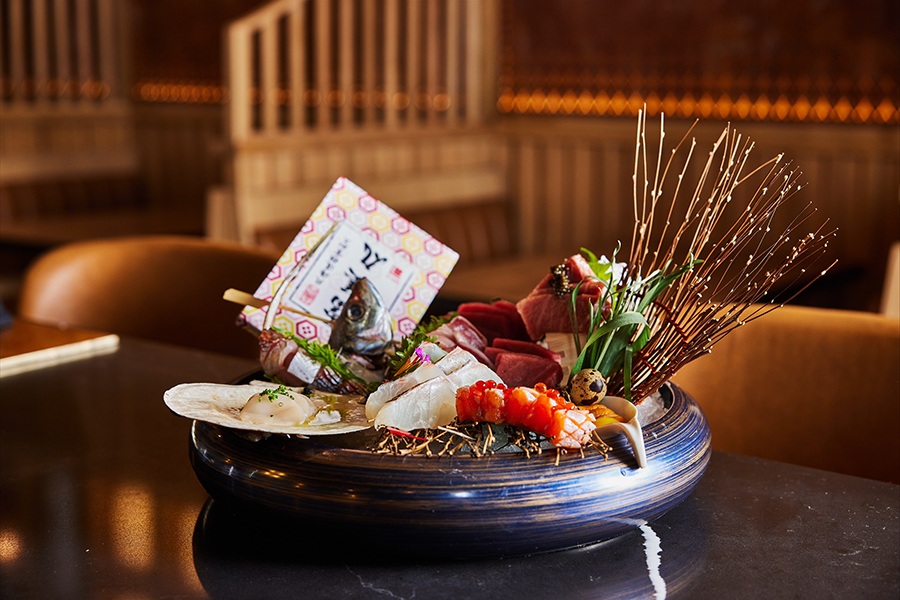 An elaborate bowl of sashimi includes a fish head, quail egg, decorative items, and more.