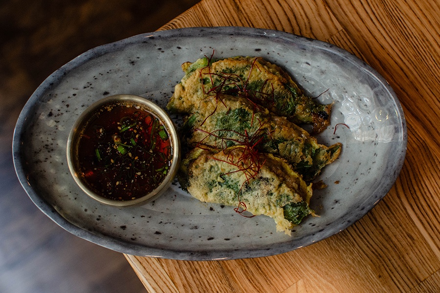 Leaves are battered, fried, and served with a small bowl of soy sauce.