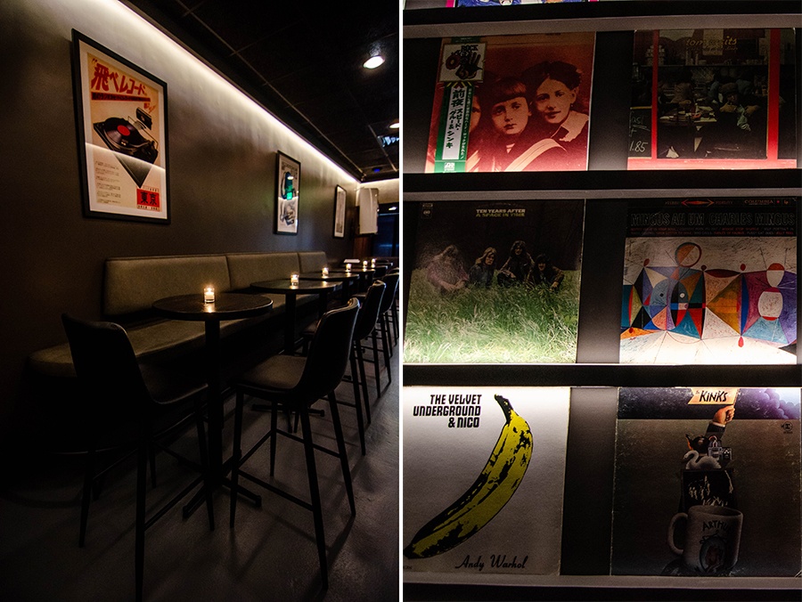 Interior view of a dark bar with black and gray walls, ceiling, and seating, with shelves of records.