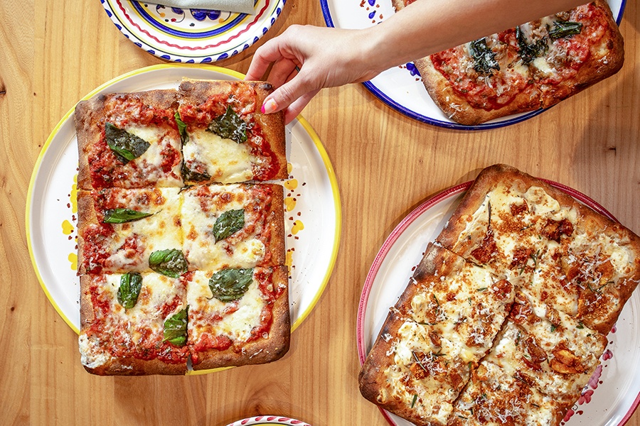 Overhead view of rectangular, thick-crust pizzas with various toppings.