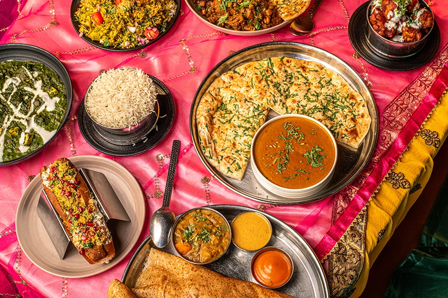 Overhead view of various dishes of Indian food on a colorful background.